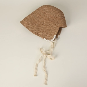 Detail of handwoven raffia hat featuring white crochet lace trim and cream lace ties