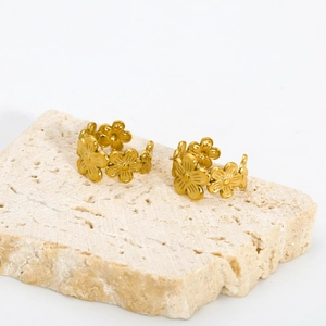 Detail view of 18K gold-plated double-layer floral ear cuffs on a natural stone base