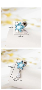 Macro detail of star-shaped silver piercing stud with light blue zircon and water drop stone