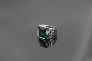 Macro shot of retro steel ring featuring a rectangular green gemstone and floral engravings