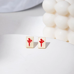 Detail of creative Mahjong stud earrings with red character on matte gold surface