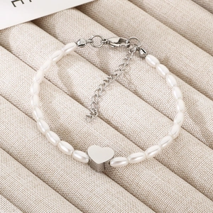 Detail of pearl heart bracelet showing glossy metal pendant and lobster clasp finish