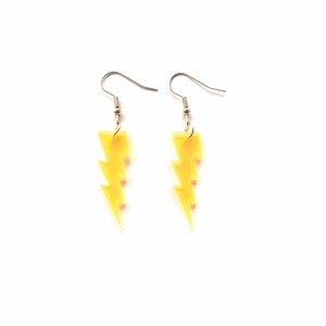 Detailed view of yellow glitter lightning acrylic earrings with golden metal hooks