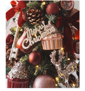 Detailed view of red velvet bows and rose gold ornaments on a decorated mini Christmas tree