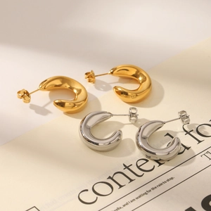 Macro view of C-shaped thick hoop earrings in gold and silver with S925 engraved hallmark