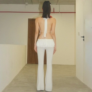 Vista posteriore del top bianco con volant e dei pantaloni a zampa aderenti abbinati
