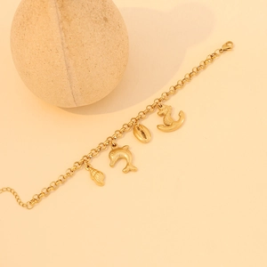 Gold stainless steel bracelet with starfish and shell charms on beige background