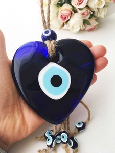 Close-up of heart-shaped blue glass Evil Eye pendant with rustic hemp rope and beads