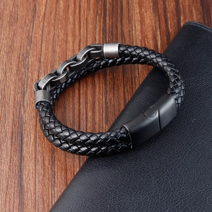 Men's braided black leather bracelet with gunmetal steel links on a dark leather wallet