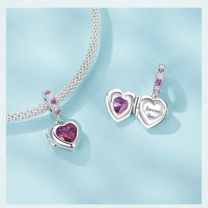 Macro detail of silver heart locket showing 'Forever Love' engraving and pink gemstone