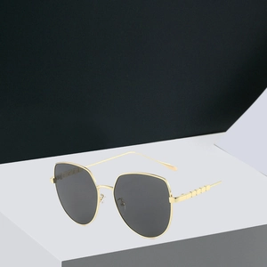 Detailed shot of gold metal cat-eye sunglasses with dark grey lenses and geometric frames