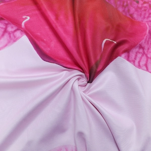 Close-up detail of smooth textile fabric with pink and red floral prints and soft texture