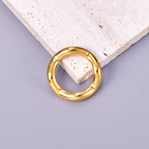 Polished wavy gold ring with hammered texture on a textured beige stone background