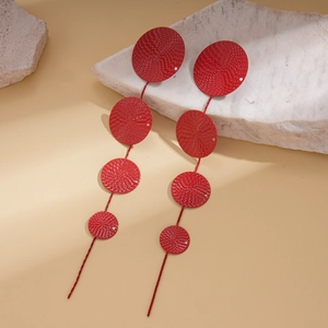 Statement long tassel earrings with four red circular metal plates on a stone display