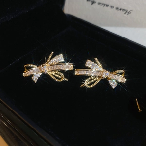 Macro shot of gold plated bow earrings with sparkling cubic zirconia on black velvet