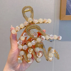 Detail of elegant gold metal hair claws with rose motifs and artificial pearl accents