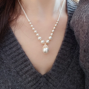 Détail d'un collier de perles plaqué or sur mannequin avec un grand pendentif en perle