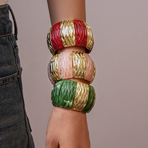 Detail of wide elastic resin bracelet with marble texture and gold wavy metal links