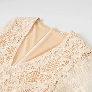 Dettaglio dell'abito in pizzo beige con profondo scollo a V sulla schiena e cerniera invisibile