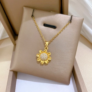 Close-up of golden sunflower pendant with sparkling crystals on a fine O-chain necklace