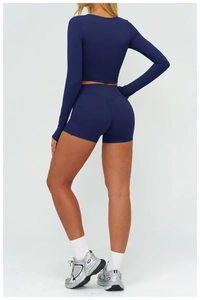 Vista posteriore del set yoga blu scuro con top a maniche lunghe e pantaloncini sportivi