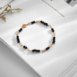 Detail of gold chain bracelet with black faceted crystal beads on an elegant magazine backdrop