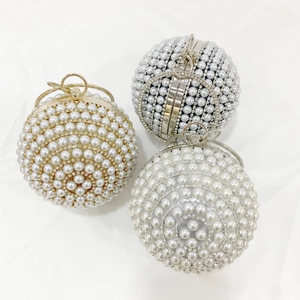 Luxurious spherical pearl evening bags in champagne, black, and white with metal ring handles