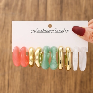 Close-up of five pairs of colorful acrylic C-shaped hoop earrings on display card