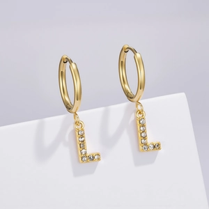 Detail of a golden letter L earring pendant with sparkling zircons on a hoop