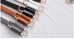 Detail of elegant PU leather waist belts with polished golden hardware for women