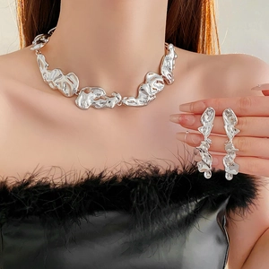 Detailed view of fluid irregular metallic necklace and earrings set on model
