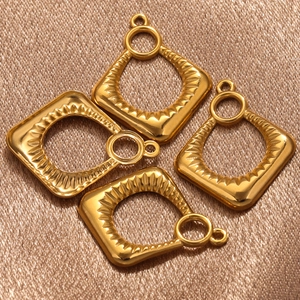 Golden diamond-shaped earrings with wave texture and hanging loops on silk background