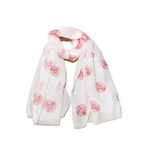Detail of red floral print on white scarf showing delicate fringe edges and soft texture