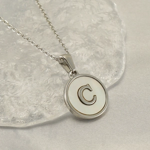 Silver stainless steel necklace with letter C pendant on white mother-of-pearl base