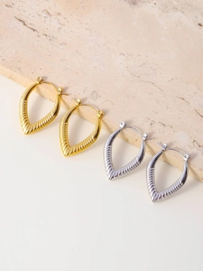 Detail of gold and silver V-shaped drop hoop earrings with radial ribbed metal texture