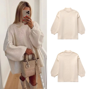 Detail view of cream oversized knit sweater with lantern sleeves and mock neck design
