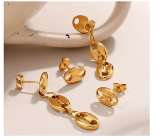 Detailed close-up of golden geometric pig nose earrings and long pendants on ceramic