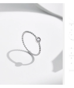 Dettaglio dell'anello in argento con perline e moissanite scintillante su fondo bianco