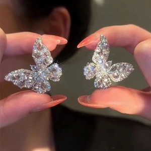 Elegant silver butterfly stud earrings with sparkling zircon stones held by hands