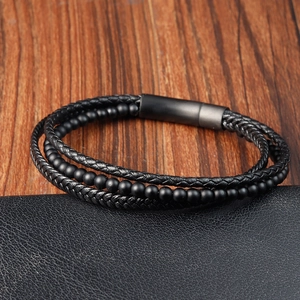 Detail of multi-layer black braided leather bracelet with matte beads and magnetic clasp