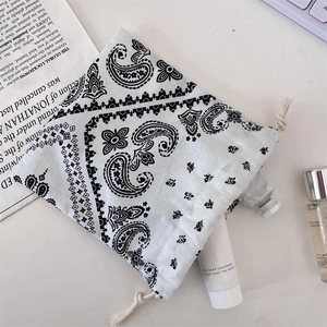 Close-up of black and white paisley drawstring pouch organizing hand cream and cosmetics