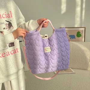 Detail van lila gewatteerde tas met hartpatroon, regenbooghandvatten en roze schouderriem