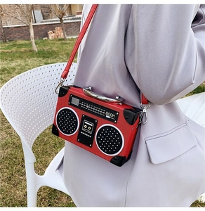Detail of red vintage radio-shaped crossbody bag with frequency scale and boom power text
