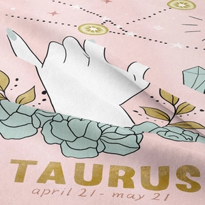 Macro view of woven Taurus zodiac tapestry fabric featuring golden print and pink texture