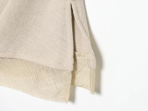 Detail von haferbeigem Strickstoff mit Seitenschlitz und hochwertiger Nahtverarbeitung