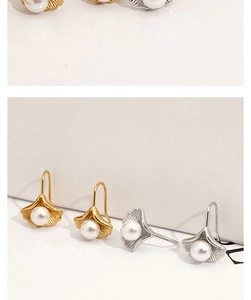 Detail of ginkgo leaf earrings with pearls in gold and silver finish on white background