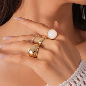 Close-up of gold geometric resin rings featuring a large opal-like stone inlay