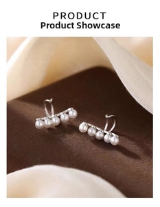 Detailed close-up of five white pearls arranged on a silver-plated minimalist ear cuff