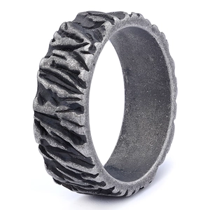 Macro view of wide silver ring band featuring rugged industrial tire tread texture