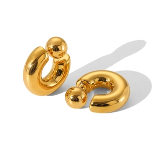 Macro shot of gold-plated thick C-shaped hoop earrings with spherical end and mirror polish